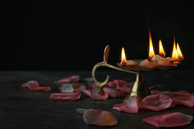 Divaly kutlama koyu arka plan üzerinde çiçek yaprakları ile diya lamba