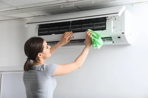 Jovem mulher limpeza ar condicionado em casa — Fotografia de Stock