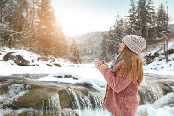 Beautiful woman with cup of hot mulled wine at snowy resort — Stock Photo, Image