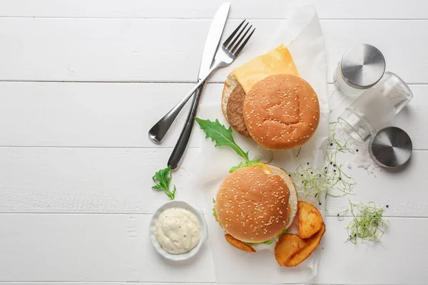 Композиция с вкусными гамбургерами на столе — стоковое фото