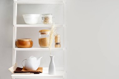 Raflar mutfak eşyaları yakınındaki beyaz duvar ile