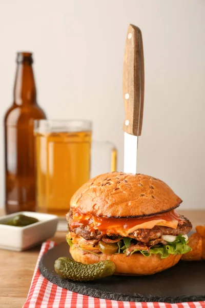 Tasty burger with knife on table — Stock Photo, Image