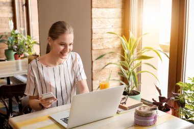 Cep telefonu ve laptop kafede çalışan genç serbest meslek