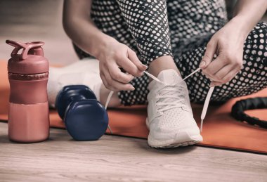 Genç kadın spor salonunda, closeup katta ayakkabı bağcığı bağlama