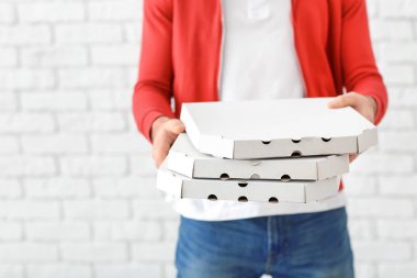 Teslimatçı tuğla duvar zemin üzerine karton pizza kutuları ile