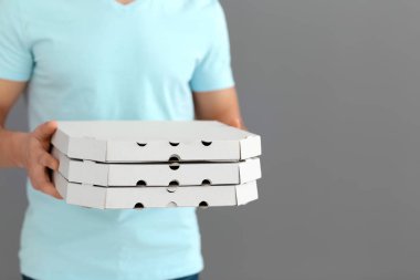 Teslimatçı ile karton pizza kutuları gri arka plan üzerinde