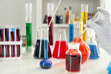 Laboratuar işçisi alarak örnek şişeyi masada kırmızı sıvı ile