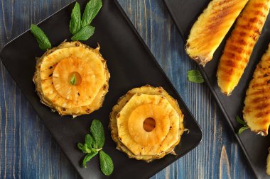 Ahşap masa üzerinde ızgara ananas dilimleri ile plaka