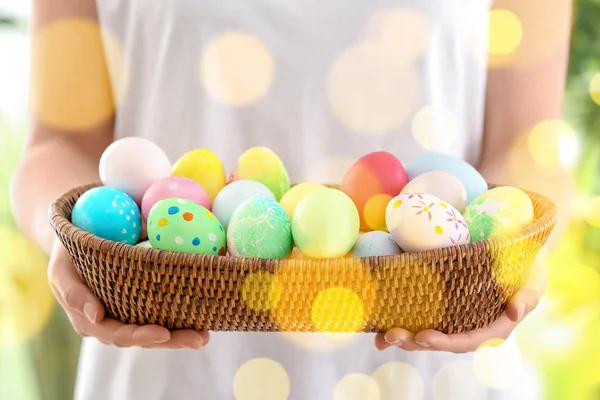 Young woman with wicker bowl full of colorful Easter eggs, closeup — Stock Photo, Image