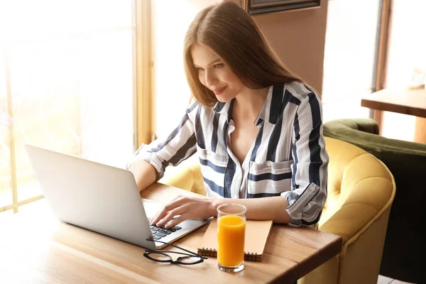 Young female freelancer with laptop working in cafe — Stock Photo, Image