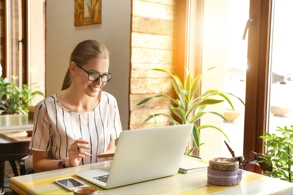 Freelancer jovem com laptop trabalhando no café — Fotografia de Stock