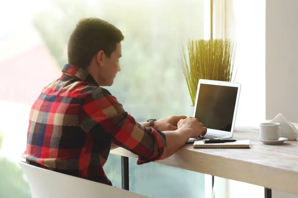 Młody freelancer działa na laptopie w kawiarni — Zdjęcie stockowe