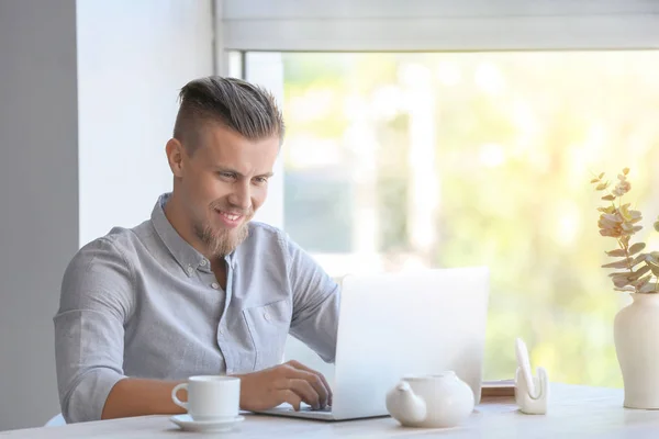 Beau pigiste travaillant sur un ordinateur portable dans un café — Photo