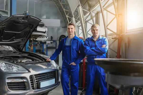 Retrato de los mecánicos masculinos cerca del coche en el centro de servicio — Foto de Stock