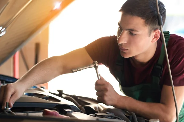 Jovem auto mecânico reparando carro no centro de serviço — Fotografia de Stock