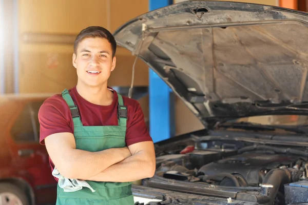 Young auto mechanic near car in service center — Stock Photo, Image