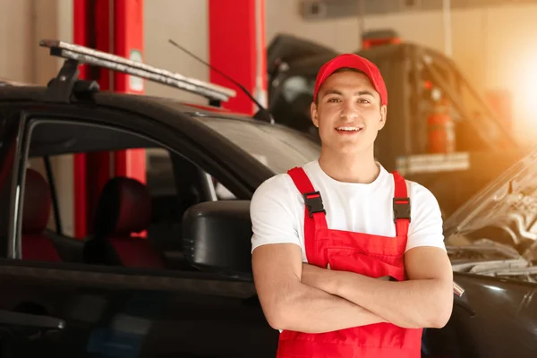 Young auto mechanic near car in service center — Stock Photo, Image