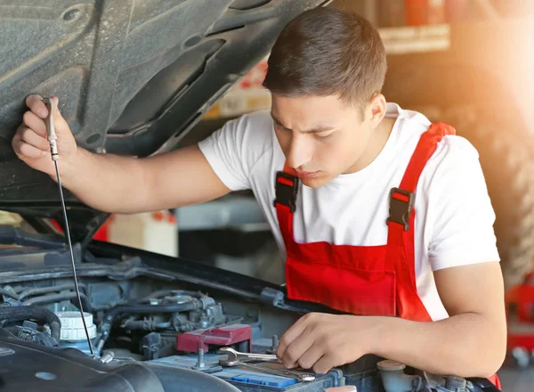 Jovem mecânico verificando o nível de óleo do motor no centro de serviço de carro — Fotografia de Stock