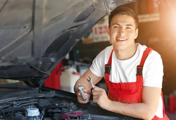 Joven mecánico de automóviles de reparación de coches en el centro de servicio — Foto de Stock