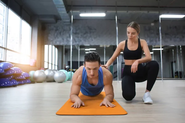 Hombre joven entrenando con entrenador en gimnasio moderno — Foto de Stock