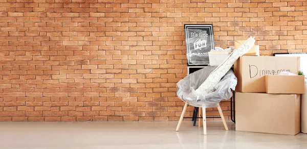 Mozgó-ba új ház, tégla fal mellett készített bútorok és karton dobozok — Stock Fotó