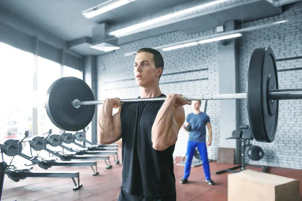 Athletic man training with barbell in modern gym — Stock Photo, Image