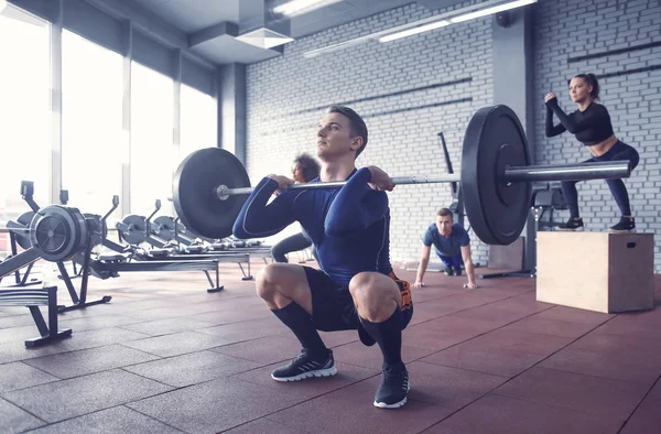 Athletic man training with barbell in modern gym — Stock Photo, Image
