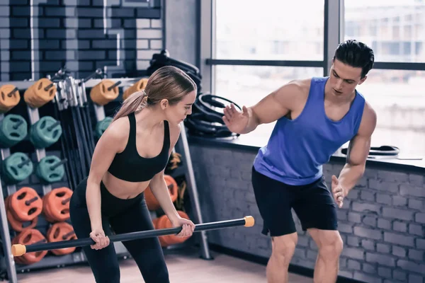 Mujer joven entrenando con el entrenador en el gimnasio moderno — Foto de Stock