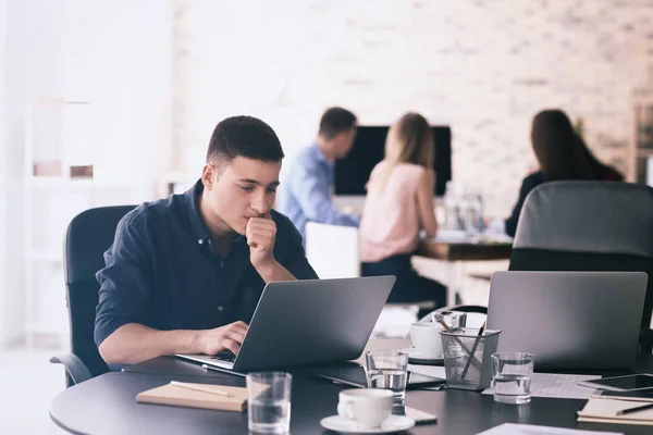 Hombre joven usando el ordenador portátil para prepararse para la reunión de negocios en la oficina — Foto de Stock