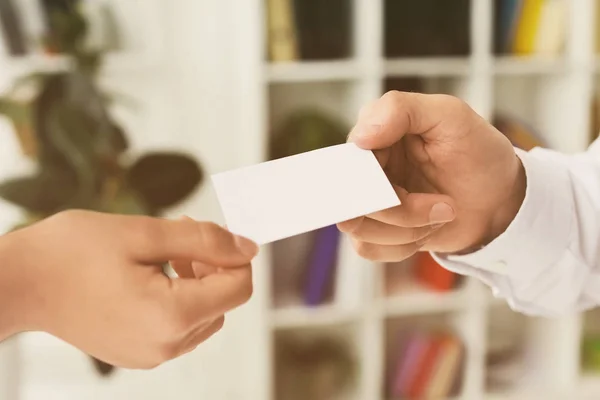 Man giving business card to woman in office, closeup — Stock Photo, Image