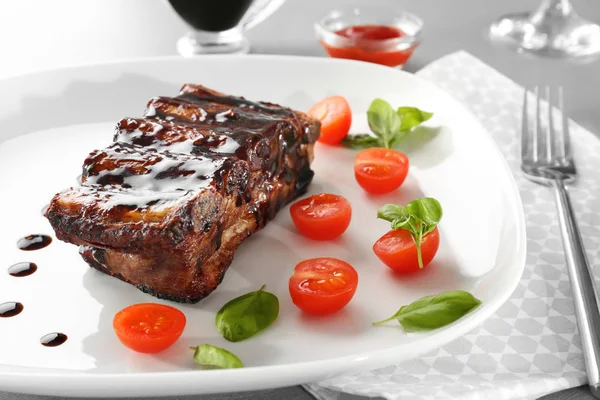 Délicieuses côtes grillées avec sauce et tomates sur assiette, gros plan — Photo