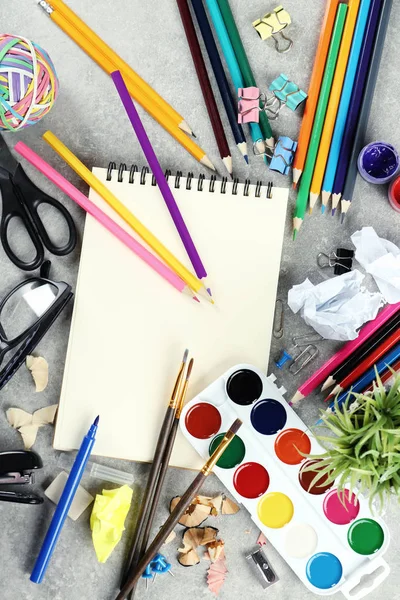 Workplace composition with paint, notebook and color pencils on table, flat lay — Stock Photo, Image