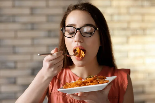 Young woman eating delicious pasta indoors — Stock Photo, Image