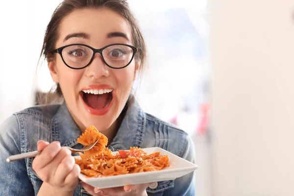 Young woman eating delicious pasta indoors — Stock Photo, Image