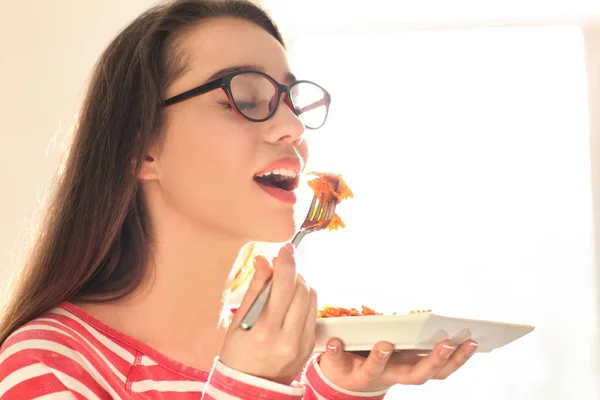 Mujer joven comiendo deliciosa pasta en el interior — Foto de Stock