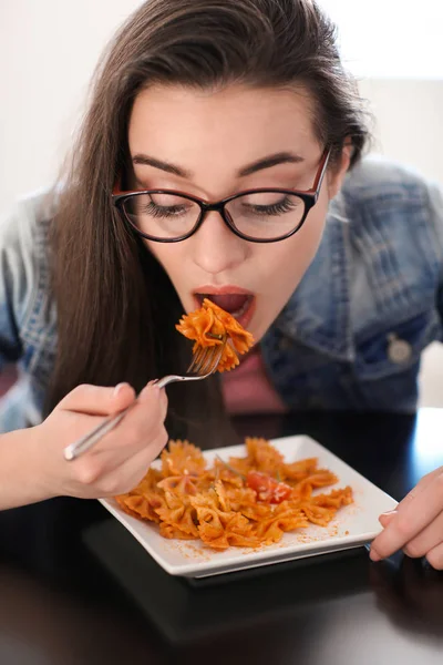 Mujer joven comiendo deliciosa pasta en el interior — Foto de Stock