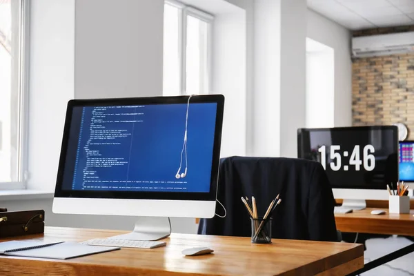 Рабочее место с компьютером, наушниками и канцелярскими принадлежностями на столе в современном офисе — стоковое фото