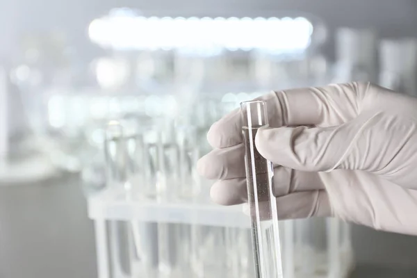 Laboratoriet arbetstagaren innehar provröret med vatten nära bord — Stockfoto