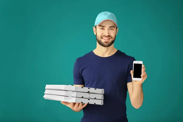 Leverans mannen med kartong pizzakartonger och telefon på färgbakgrund — Stockfoto