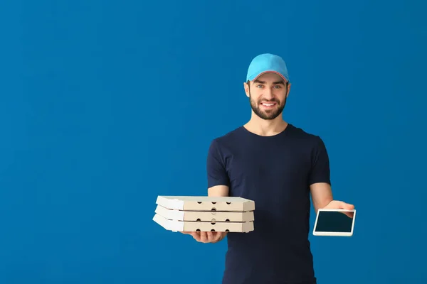 Doručovatel s lepenkové pizza krabice a tablet na barvu pozadí — Stock fotografie