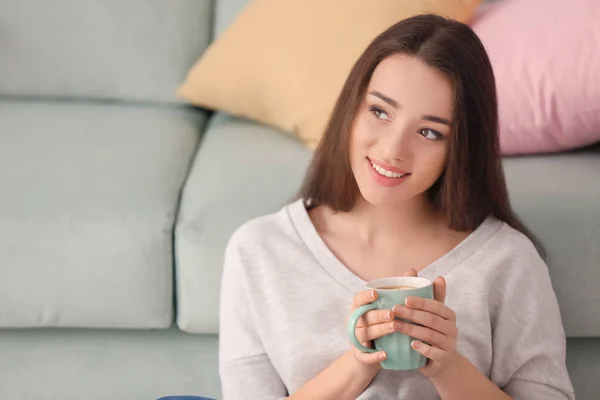 Hermosa joven con taza de té caliente en casa — Foto de Stock