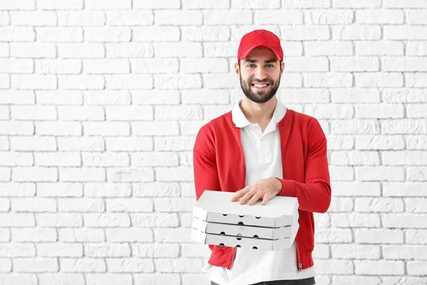 Delivery man with cardboard pizza boxes on brick wall background — Stock Photo, Image