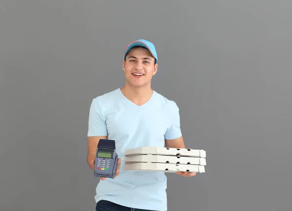 Delivery man with cardboard pizza boxes and payment terminal on grey background — Stock Photo, Image