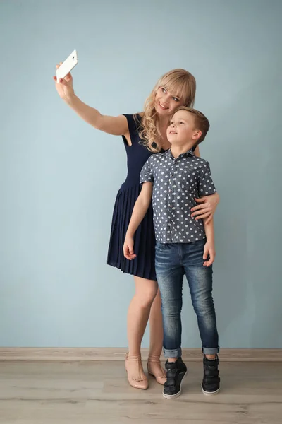 Young woman taking selfie with her son indoors — Stock Photo, Image