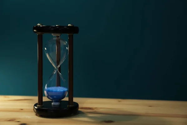 Кришталевий пісочний годинник на столі на фоні кольору. Концепція управління часом — стокове фото