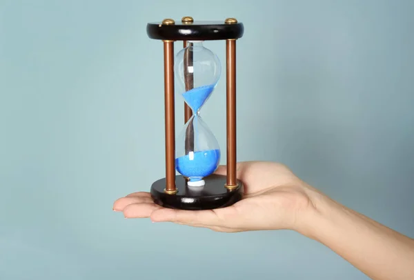 Woman holding hourglass on color background. Time management concept — Stock Photo, Image