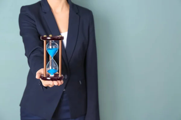 Женщина держит песочные часы на цветном фоне. Концепция управления временем — стоковое фото