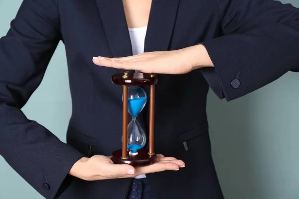 Жінка тримає пісочний годинник на кольоровому фоні, крупним планом. Концепція управління часом — стокове фото