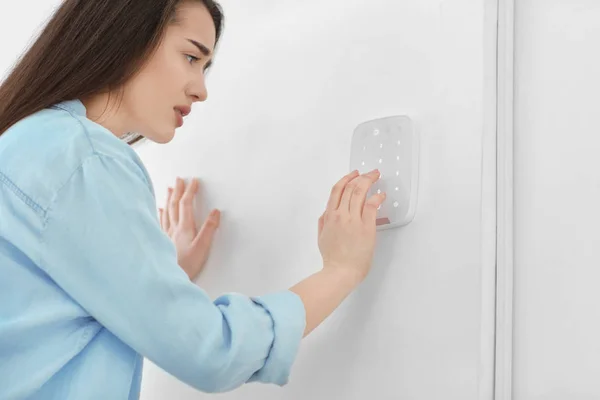 Donna spaventata utilizzando il sistema di sicurezza all'interno — Foto Stock