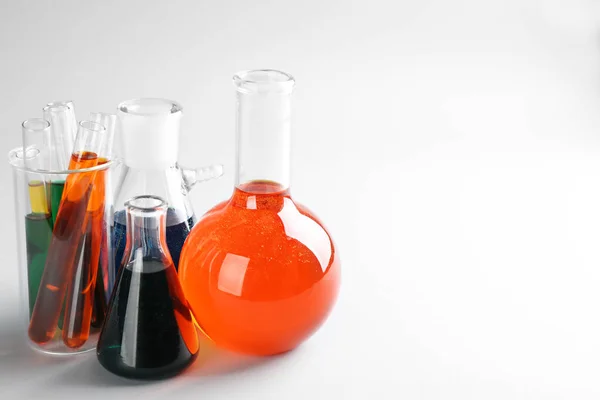 Cristalería química con líquidos de colores sobre fondo claro — Foto de Stock